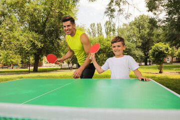 Happy man with his son playing ping pong in park