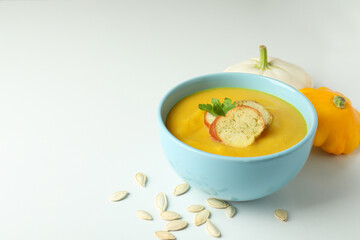 Pot with pumpkin soup and ingredients on white background