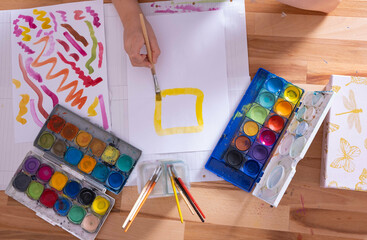 the child draws with colored paints, draws a square with a brush