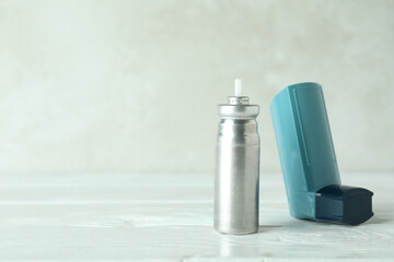 Blue asthma inhaler on white wooden table