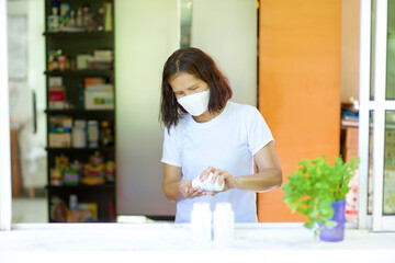 Asian woman self quarantine at home taking medication.Lady having medicine or supplement for illness while wearing mask.Adult boosting immune system with vitamin C.
