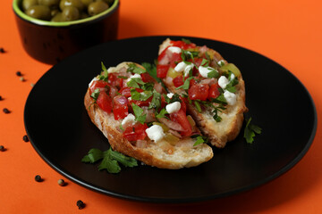 Delicious italian snacks bruschetta and ingredients on orange background