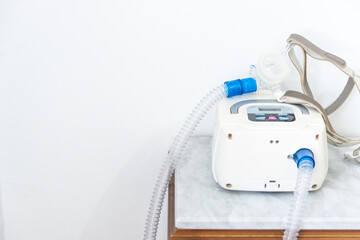 CPAP machine with air hose and head mask on bedside table