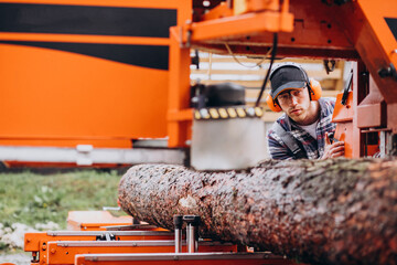 Carpenter working on a sawmill on a wood manufacture