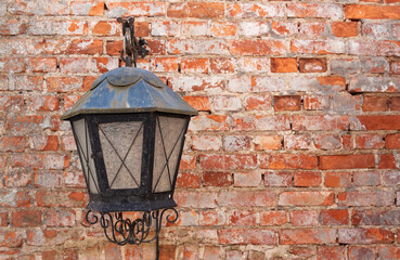 Old metal, black coloured lamp hanging at the red, old brickwall