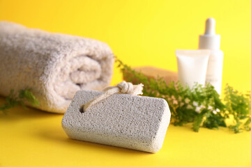 Pumice stone and towel on yellow background