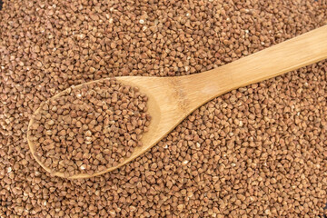 Wooden spoon in a heap of buckwheat. Healthy food and lifestyle. Copy space. Top view.