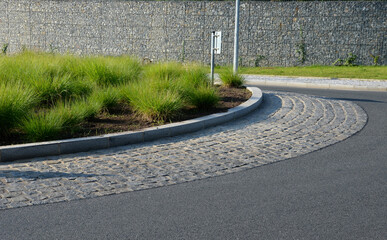 roundabout of gray granite cubes closer to the center. beveled concrete curbs with flowers and...