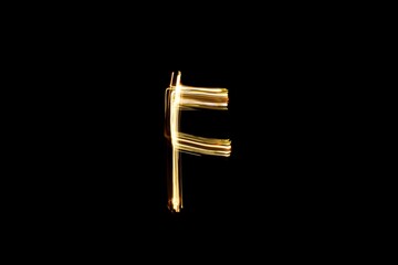 Drawn letter F with gold lights against black background. Light painting alphabet.