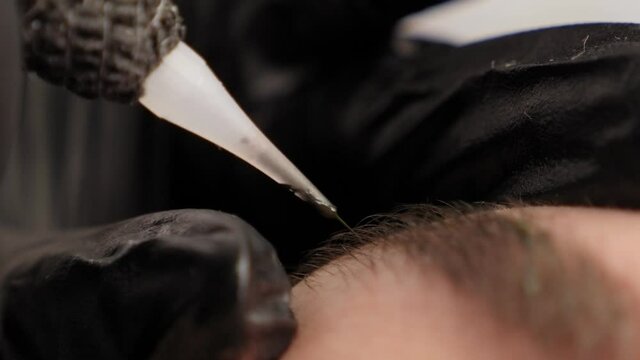 Close-up of a beautician doing permanent eyebrow makeup for a young woman in a beauty salon.