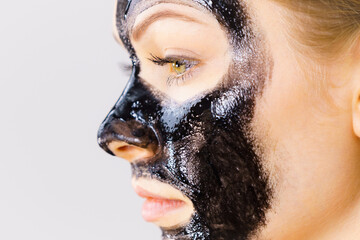 Woman applying black cleanser mask to face