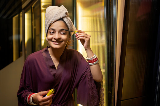 Young newlywed woman applying mascara in front of the mirror.