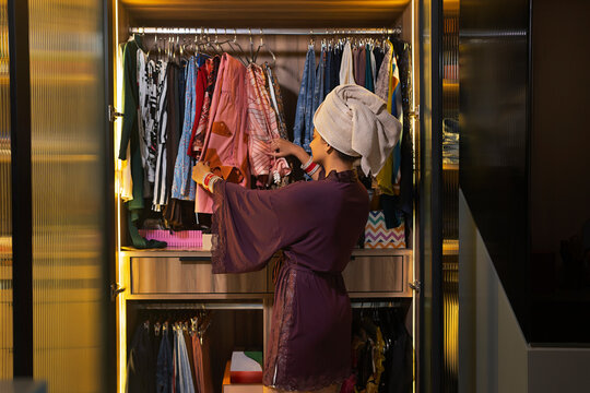Young newlywed woman picking clothes from her closet.
