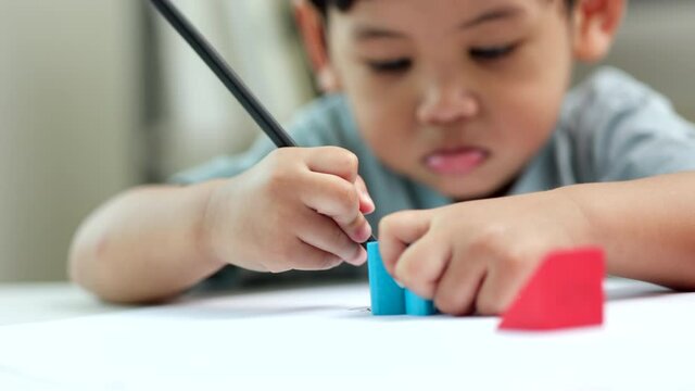 Asian little boy education from home. Developing children's learning before entering kindergarten Practice the skills of playing with wooden toys and drawing and painting.
