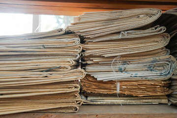Neat stack of old newspapers with close up detail of the corner of the pile