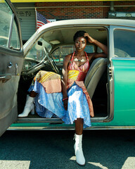 Portrait of young fashionable woman sitting in vintage car
