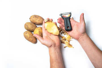 The guy peels potatoes on a white background, next to it lies potatoes and peel