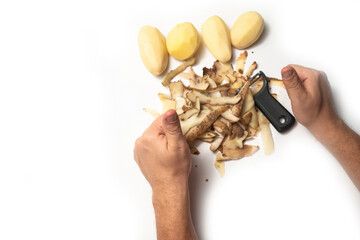 The guy peels potatoes on a white background, next to it lies potatoes and peel