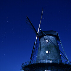 Scenic view of an old windmill on a dark stary stary - obrazy, fototapety, plakaty