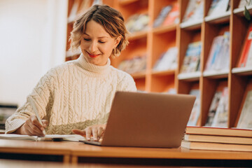 Young woman working on laptop in a library