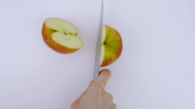 Gala apple is cut into four pieces on a white cutting board.