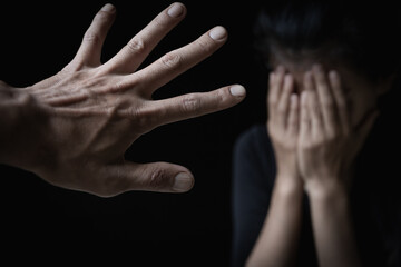 Fototapeta premium Men's hands will hurt women. Women bow their heads and cover their hands. Concept of sexual harassment, human trafficking, family rape. Harassment to the defenseless. International Women's Day.