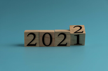 Wooden cube with word 2021 change to 2022. New Year concept on blue background. Closeup and copy space on top and under for design or text.