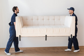 side view of movers carrying white couch in living room