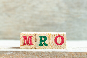 Alphabet letter block in word MRO (Abbreviation of Maintenance, repair and overhaul or Maintenance, Repair and Operations) on wood background - obrazy, fototapety, plakaty