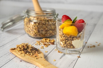 Delicious homemade granola in a glass jar on white wooden background
