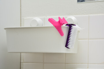 A white plastic organizer holding by two suction cup on a wall in a female bathroom
