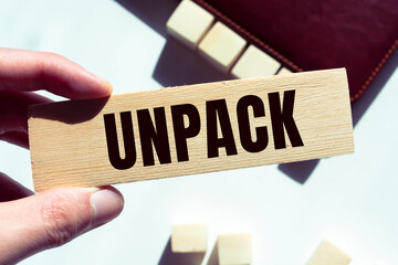 Modern business buzzword - unpack. Word on wooden blocks on a brown background. Close up.