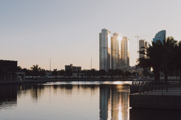 Golden City Skyline with Skyscrapers at Sunset Time Outdoor with Water Lake Around and Blue Sky