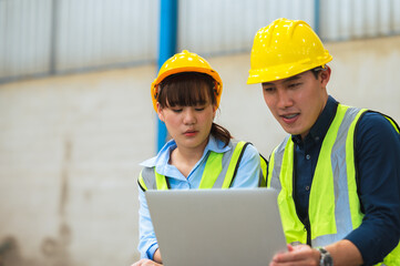 Team engineers and foreman wear a mask, hard hat, and vest. Standing consult discuss industrial production management. Explaining job details through laptops and tablets in factories or warehouses.