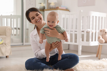 Happy young mother with her cute baby on floor at home