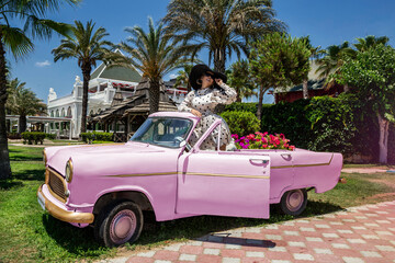 Summer fashion. Beautiful sexy elegant woman in polka dot dress near the pink car on Cuba Havana. Spring and summer fashion model concept. Vintage and retro style. Luxury travel.