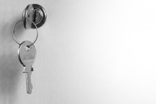Monochrome image of a key in a keyhole. Key on a white background. Keyhole blending into a white background.