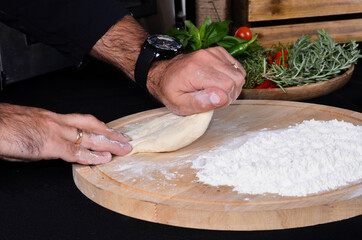 Pizza maker's hands kneading the dough. The cook makes pizza.