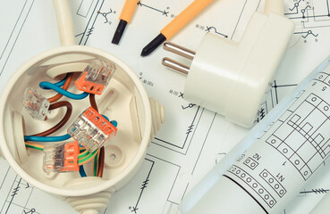 Electrical box with connections of electric copper wires and construction drawing of house. Components using in electrical installations