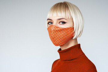 Woman wearing orange polka dot cloth protective handmade face mask during quarantine of coronavirus...