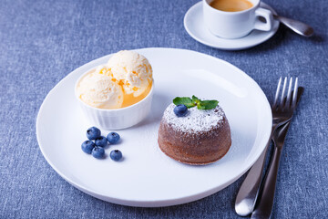 Lava cake - chocolate fondant cake with vanilla ice cream, blueberries, mint and coffee. Traditional French pastries. Close-up.