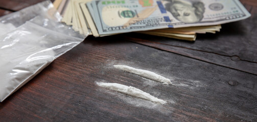 Cocaine plastic packets and American dollars banknotes on wooden table background, closeup. Drugs...