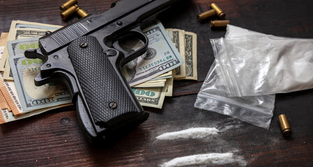 Drugs narcotics business concept. Cocaine plastic packets, gun and US dollars banknotes on a table....