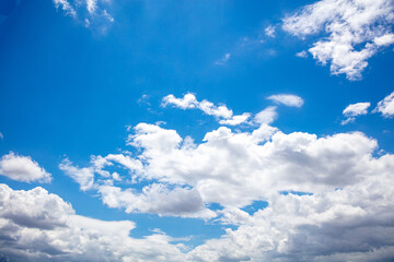 Fluffy cumulus clouds on blue sky background. Cloudscape white and grey color