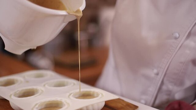 Pocess of professional confectioner making desetr on kitchen. Woman pouring crem into container for freezing
