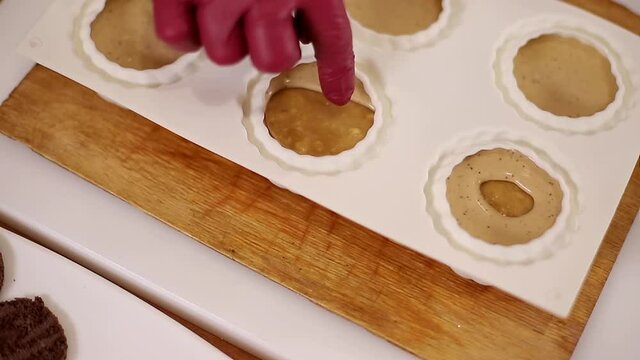 Pocess of professional confectioner making desetr on kitchen. Woman pouring crem into container for freezing
