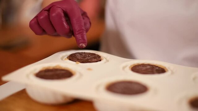 Pocess of professional confectioner making desetr on kitchen. Woman pouring crem into container for freezing