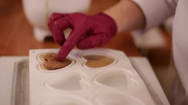Pocess of professional confectioner making desetr on kitchen. Woman pouring crem into container for freezing