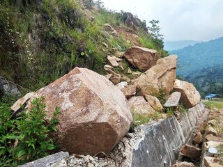 Pile of boulders on the side of the highway in a mountainous hill area
