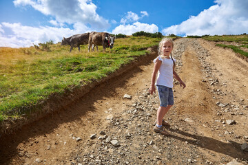 Little beautiful girl walks on a background of mountains.